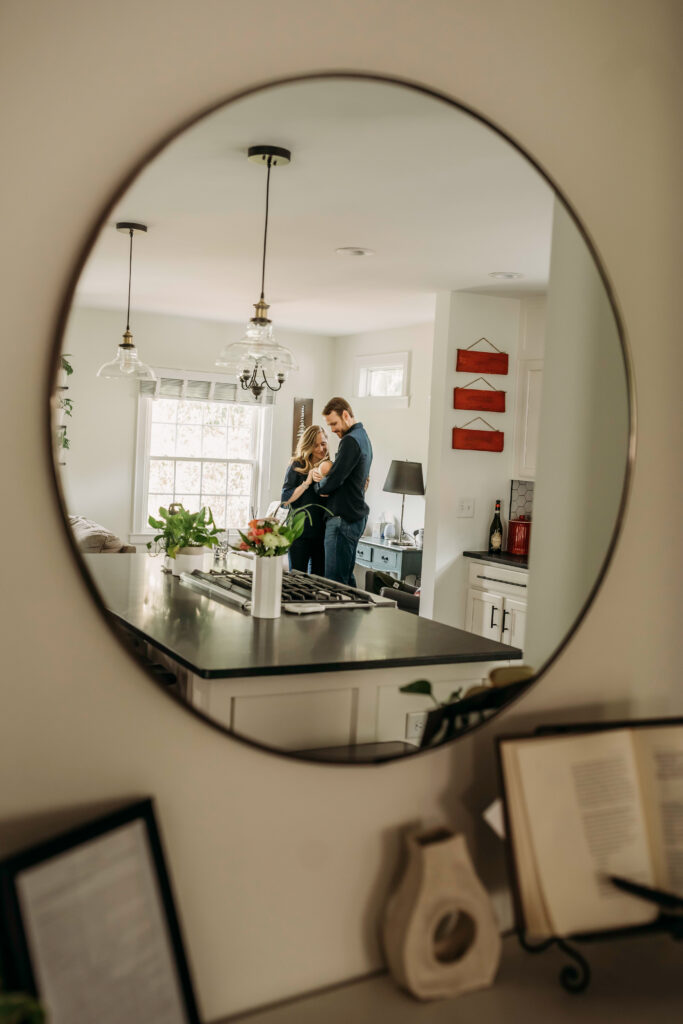 Mirror reflection of family standing in kitchen during lifestyle newborn session