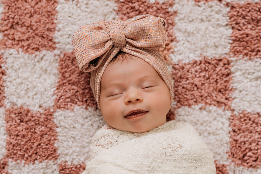 baby girl with checkered rug as backdrop