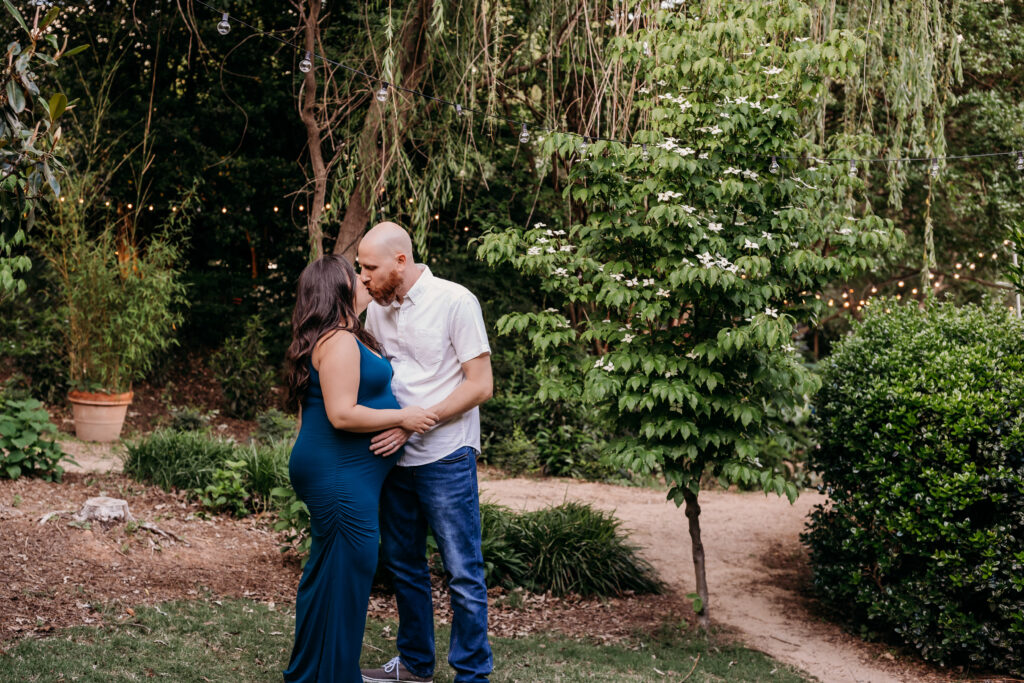 pregnant couple kissing under weeping willow tree