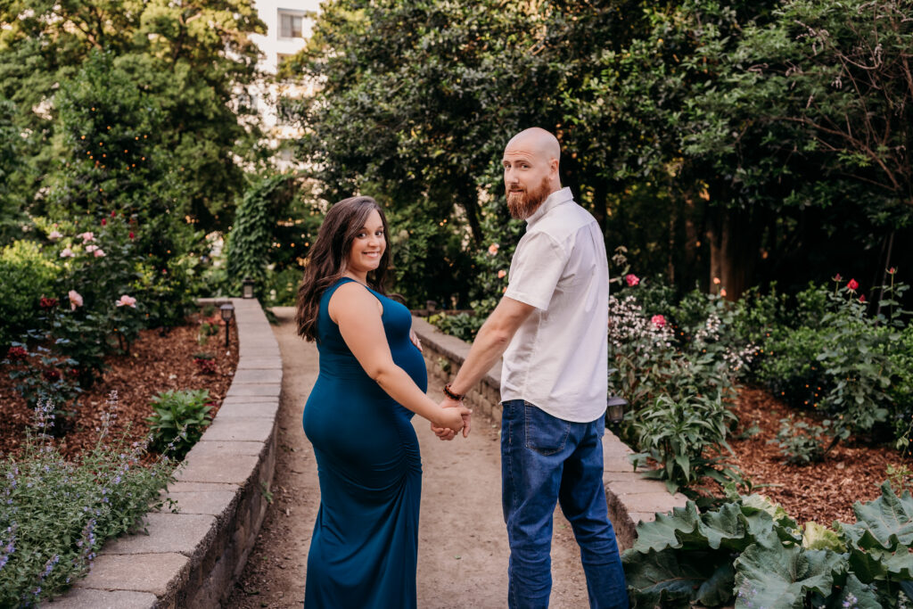maternity couple in teal dress looking at camera and holding hands